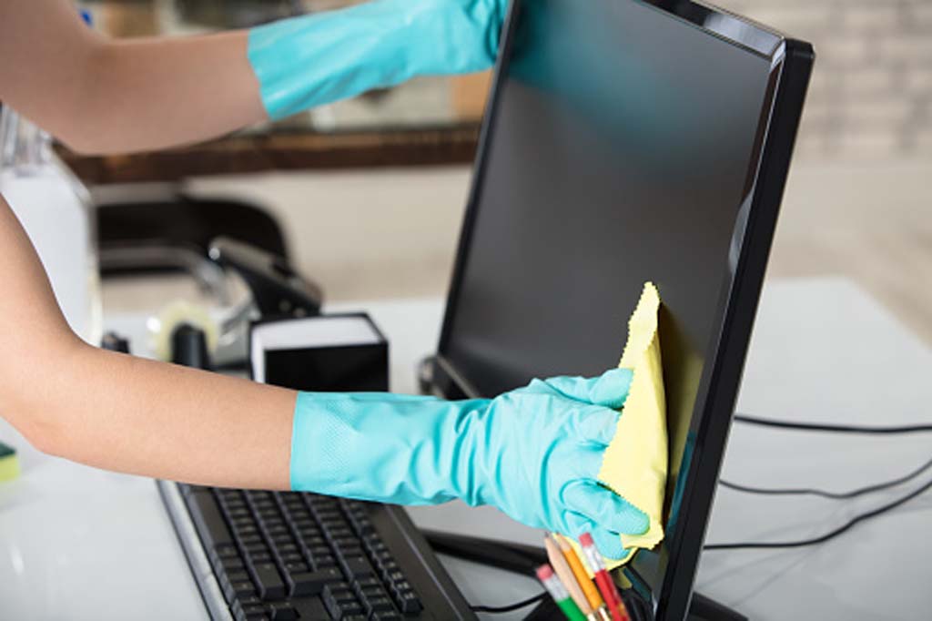 Close-up Of A Woman's Hand Cleaning The Desktop Screen With Yellow Rag In Office